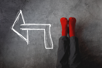 Male legs with red socks leaning on gray wall upside down with drawn direction arrow pointing to left. Youth education youth guidance student guide consultation advisory concept.